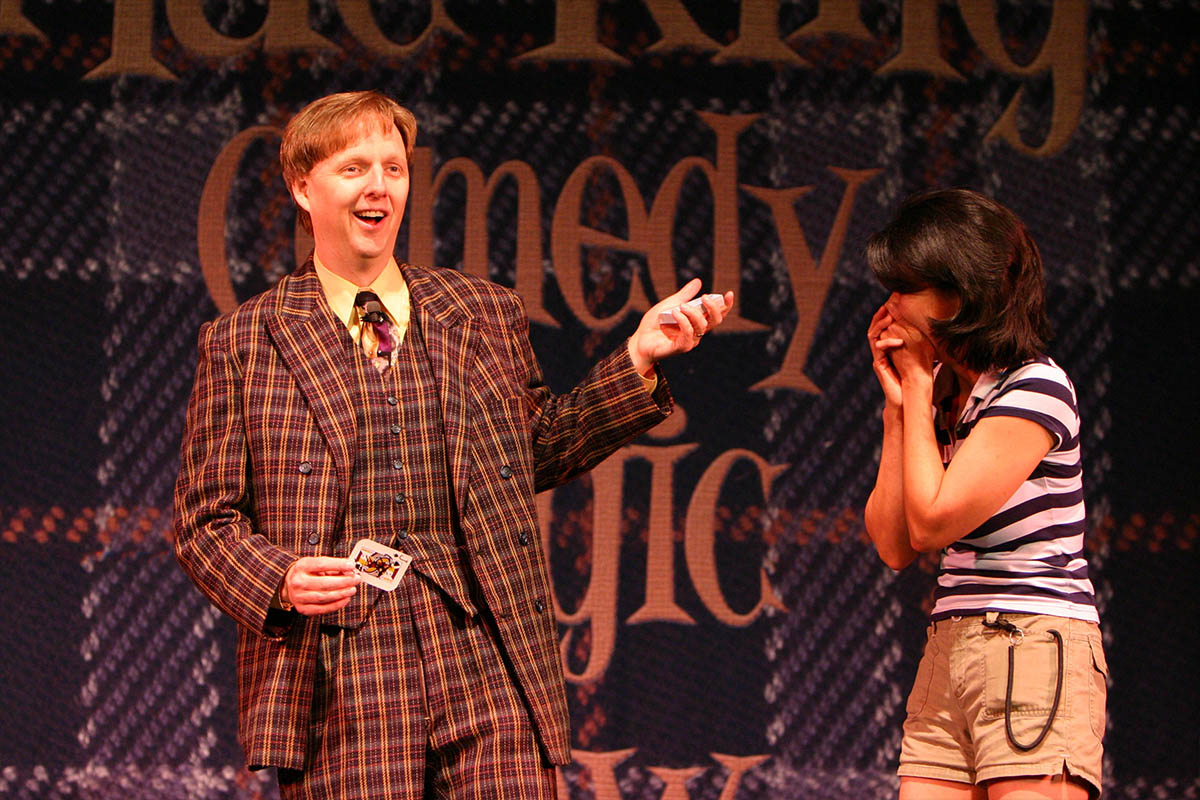 Mac King performing a card trick on stage at Thunderland Theater, Excalibur