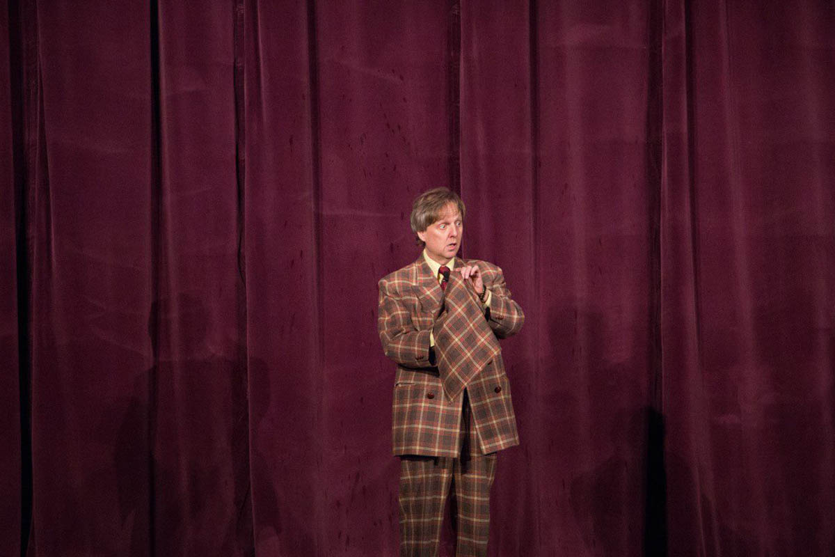 Mac King in his signature plaid suit on stage at Thunderland Theater, Excalibur